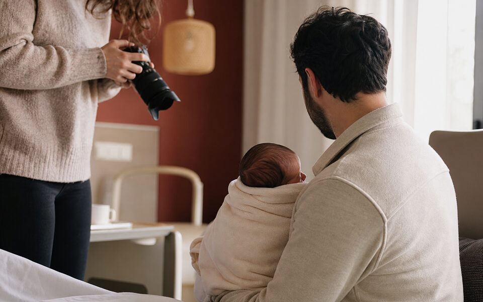 Photographe naissance urgence à Toulouse : maman et bébé, photographe en arrière-plan.